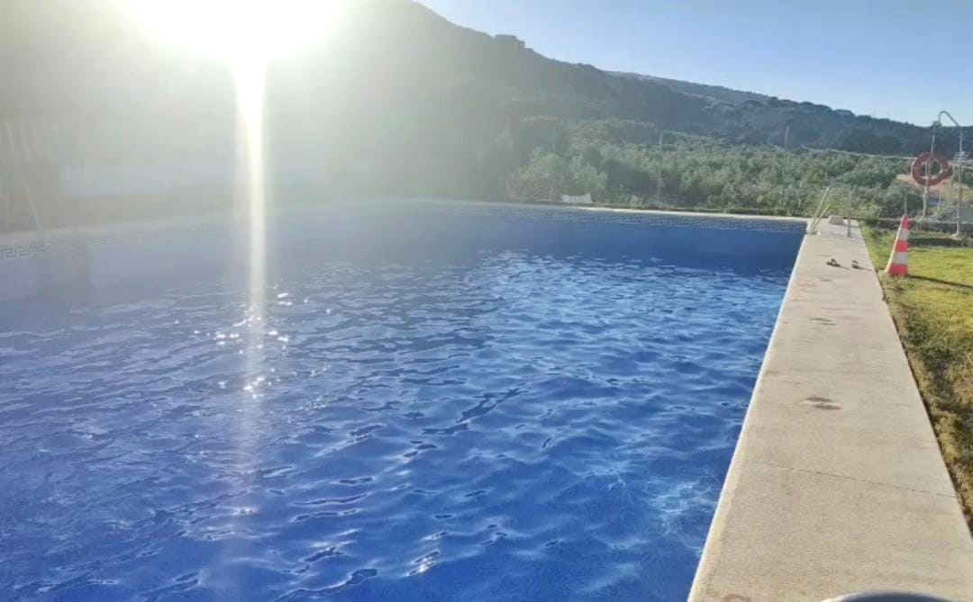Texto alternativo: Piscina soleada al aire libre con agua cristalina y vistas a la sierra en Camping El Cantonet, Albanchez de Mágina (Sierra Mágina, Jaén)